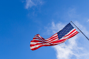 American flag is flying in the wind on a sunny day. Symbol of the Amenrican national holiday. Independence Day - American concept. Waving United states of America famous flag.