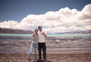 pareja de enamorados disfrutando vacaciones en cordillera de los andes junto a laguna color turquesa © Juan