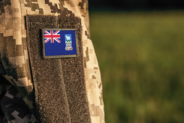 Close up millitary woman or man shoulder arm sleeve with Falkland Islands flag patch. Falkland Islands troops army, soldier camouflage uniform. Armed Forces, empty copy space for text
