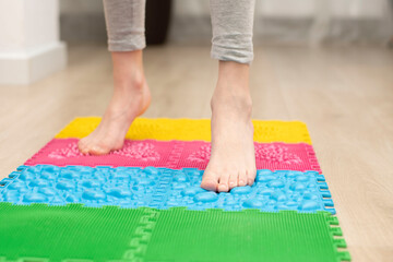 People. Healthy lifestyle. a teenager boy stands on a multi-colored orthopedic massage mat with bare feet.