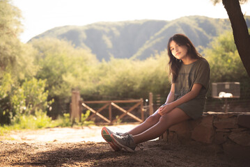 mujer sentada en cantero de piedra al atardecer
