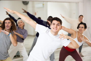 Fototapeta na wymiar Smiling dark-haired young guy attending group choreography class, learning modern dynamic dances. Concept of active lifestyle ..