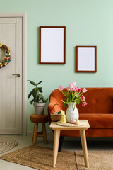 Vase with tulips, Easter bunny and eggs on end table in living room