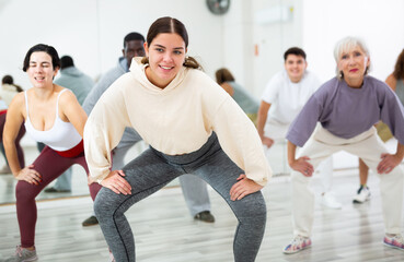 Fototapeta na wymiar Cheerful sporty young girl having fun and dancing hip hop during workout in group dance class for adults
