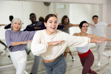 Fototapeta na wymiar Energetic sporty young girl practicing modern vigorous dance movements in group dance class ..