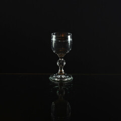 Glass on a black background. Vodka glass. A transparent glass for water or vodka. Glass cup
