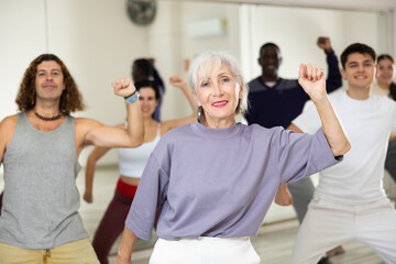 Obraz premium Active people of different nationalities are engaged in group class in a dance studio, practicing new modern dance techniques