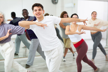 Fototapeta na wymiar Group of active people engaged in a dance studio practicing energetic swing during lesson