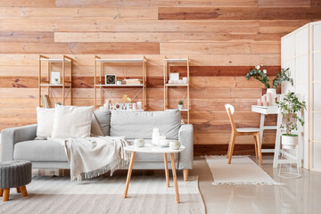 Interior of cozy living room with burning candles, sofa and shelving units