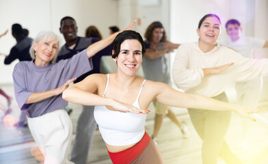Group of active people engaged in a dance studio practicing energetic swing during lesson