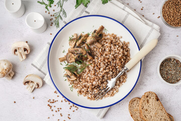 Plate of tasty buckwheat porridge with mushrooms and dill on grey table