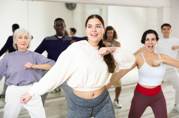 Fototapeta premium Cheerful young lady learning new modern dance in group dance lesson