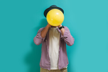 Portrait of a funny hipster guy inflating a balloon. Happy birthday concept, celebration, party. Crazy emotions. Discounts, sales, seasonal sales. Colorful summer concept.