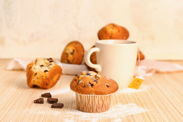 Delicious muffin with chocolate on beige wooden table