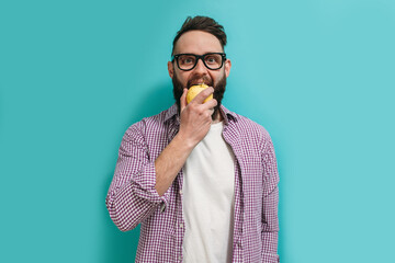 A cute healthy bearded guy in a hat eats a ripe apple. Healthy food concept