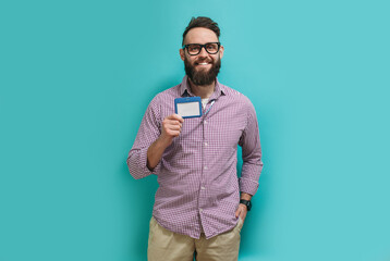 Young caucasian man with a beard in glasses for vision with a blank badge isolated on a blue color background