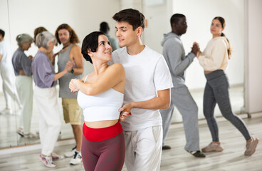 Fototapeta na wymiar Dancing positive couples learning salsa in a dance school lesson