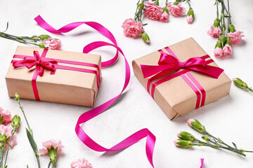 Composition with beautiful gifts and carnation flowers for Women's Day celebration on light background