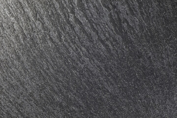 Surface of slate stone of layers, dark background, close-up top view, wallpaper, rough uneven