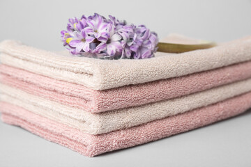 Fototapeta na wymiar Stack of soft towels and hyacinth flower on white background, closeup