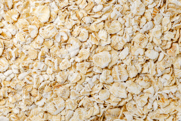 Oat flakes raw, steamed and flattened croup in bulk, close-up, background wallpaper, uniform...