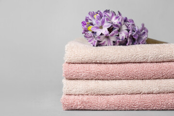 Stack of soft towels and hyacinth flower on white background, closeup