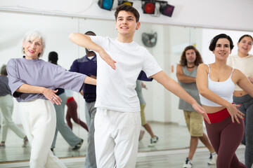 Fototapeta na wymiar Caucasian guy practising dance moves with other people in dance studio