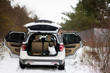 Car suv with open doors and trunk stand in winter forest.
