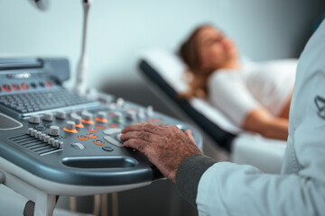 Doctor and patient. Ultrasound equipment. Diagnostics. Sonography. Closeup of male doctor moving ultrasound probe on pregnant woman's stomach in hospital. Pregnant woman getting ultrasound from doctor