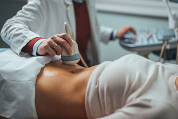 Pregnant woman undergoing ultrasound test at gynecologist office. Closeup of male doctor moving...