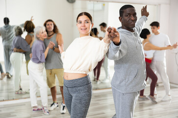 African man and caucasian young woman learning paired latin dances