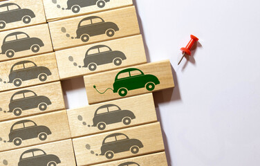 Top view of green electric car between polluting fossil combustion vehicles. Wooden cut