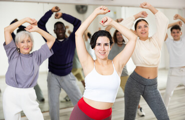 Enthusiastic young Hispanic woman attending group choreography class, learning modern dynamic dances