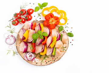 Raw chicken skewers with vegetables, peppers, onions, on a white background.Uncooked mixed meat skewer with peppers.Skewers with pieces of raw meat, red, yellow and green pepper.Top view.