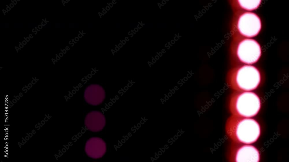 Wall mural vertically falling magenta blur light dots. magenta bokeh with reflexes fall down on a black backgro