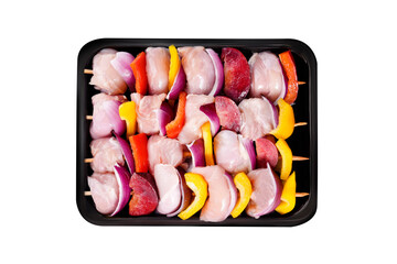 Raw chicken leg meat skewers with vegetables, plums, peppers, onions, in a tray on a white background.Top view.Close-up.Raw uncooked Chicken meat, kebab on skewers.