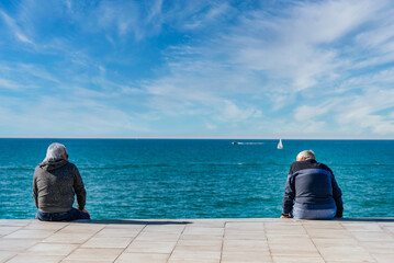 Older men sitting by the seashore talking on a sunny day