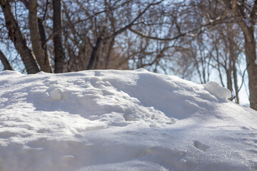 Close up view of a mound of white snow, beginning to melt under natural sunlight
