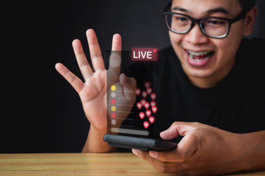 Influencer feedback of creator from subscribers or users. The man makes live content. On smartphone, a hologram shows an emotion and a feeling. Such as Love sign. Evaluation and satisfaction concept.