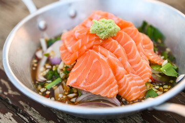 salmon fillet with wasabi on spicy sauce , fresh raw salmon salad on wooden table - Thai food