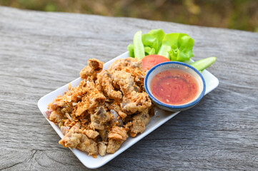 Fried pork intestine with garlic with sauce on plate - pork offal Thai food or snacks