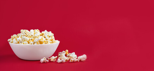 Scattered tasty cheese popcorn in bowl isolated on red background. Wallpaper, banner, header with copy space for text