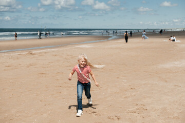 Little girl play along the beach by the sea.
