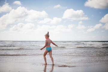 Fototapeta premium Little girl play along the beach by the sea. 