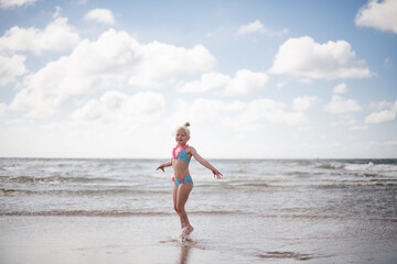 Fototapeta premium Little girl play along the beach by the sea. 