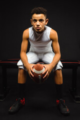 Young Youth Preteen Boy Football Player Sitting with Football on Bench in Studio