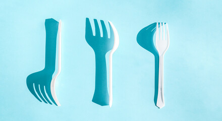 Three plastic white forks lie differently on a blue background.