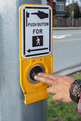 Hand pressing a button at traffic lights on pedestrian crossing. Pushing button for traffic light. Use traffic lights