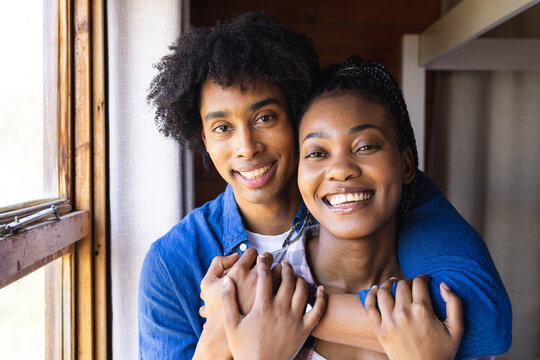 Portrait of happy african american couple spending time in log cabin and embracing