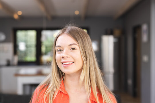 Portrait of happy caucasian teenage girl smiling in kitchen